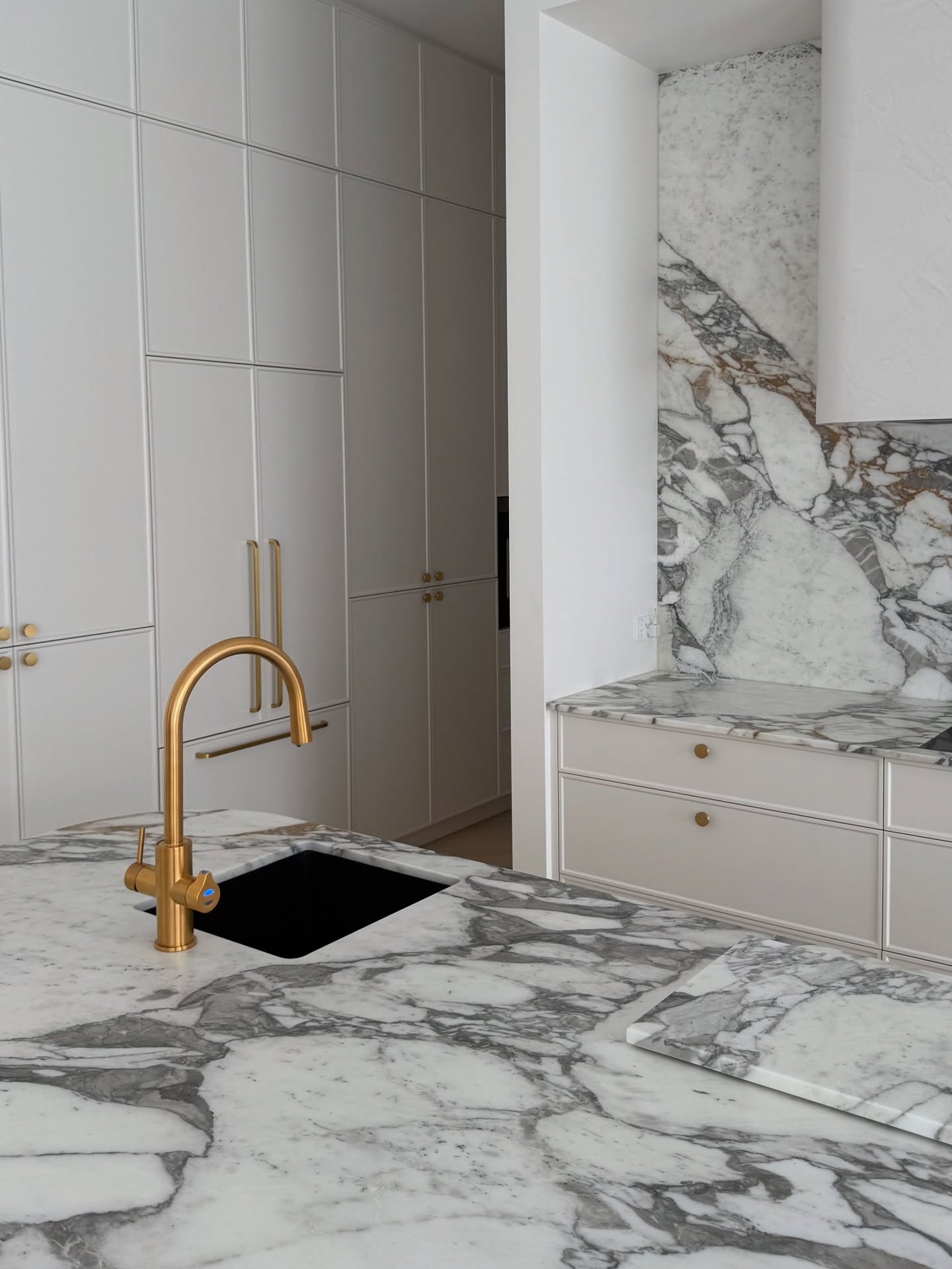 Light grey shaker kitchen with marble benchtop and brushed gold tapware