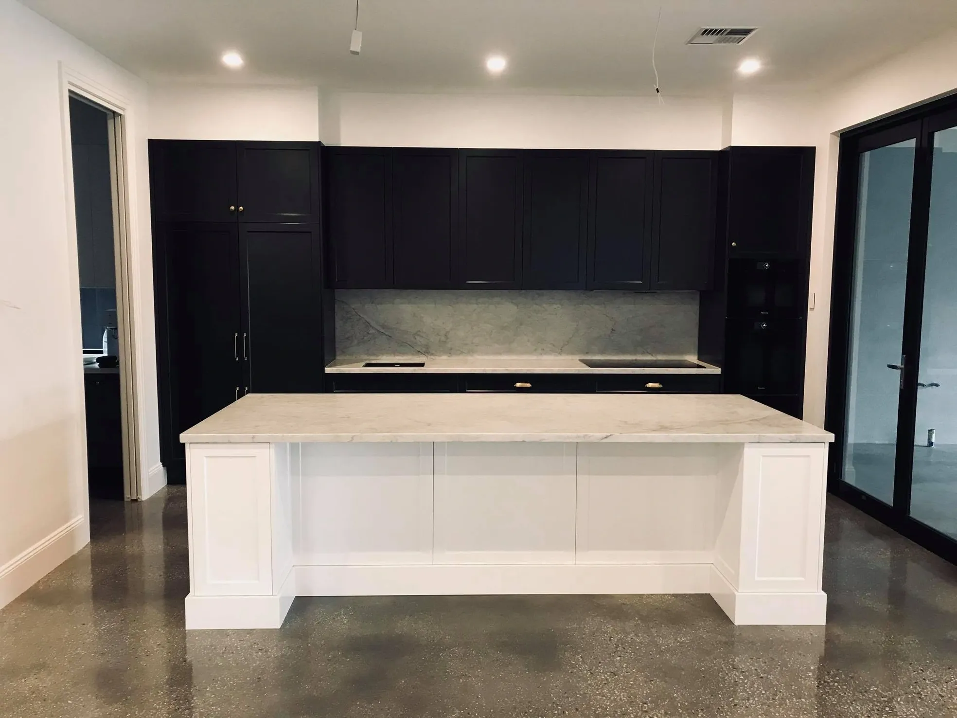 Navy shaker kitchen with white marble island bench and polished concrete floors