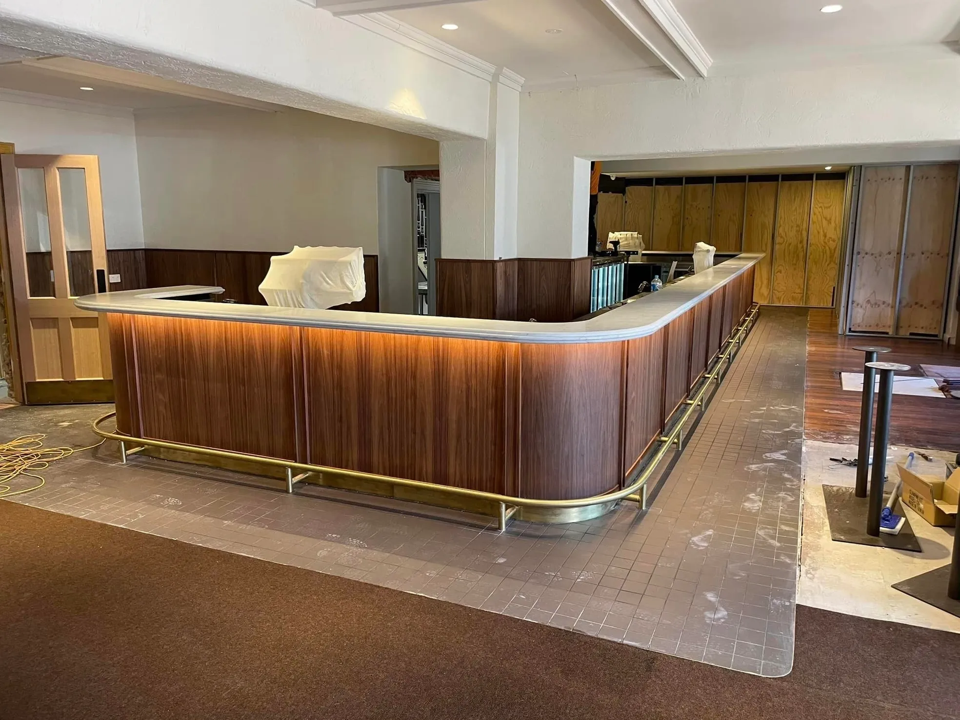 Curved timber reception counter with brushed brass base rail and stone top