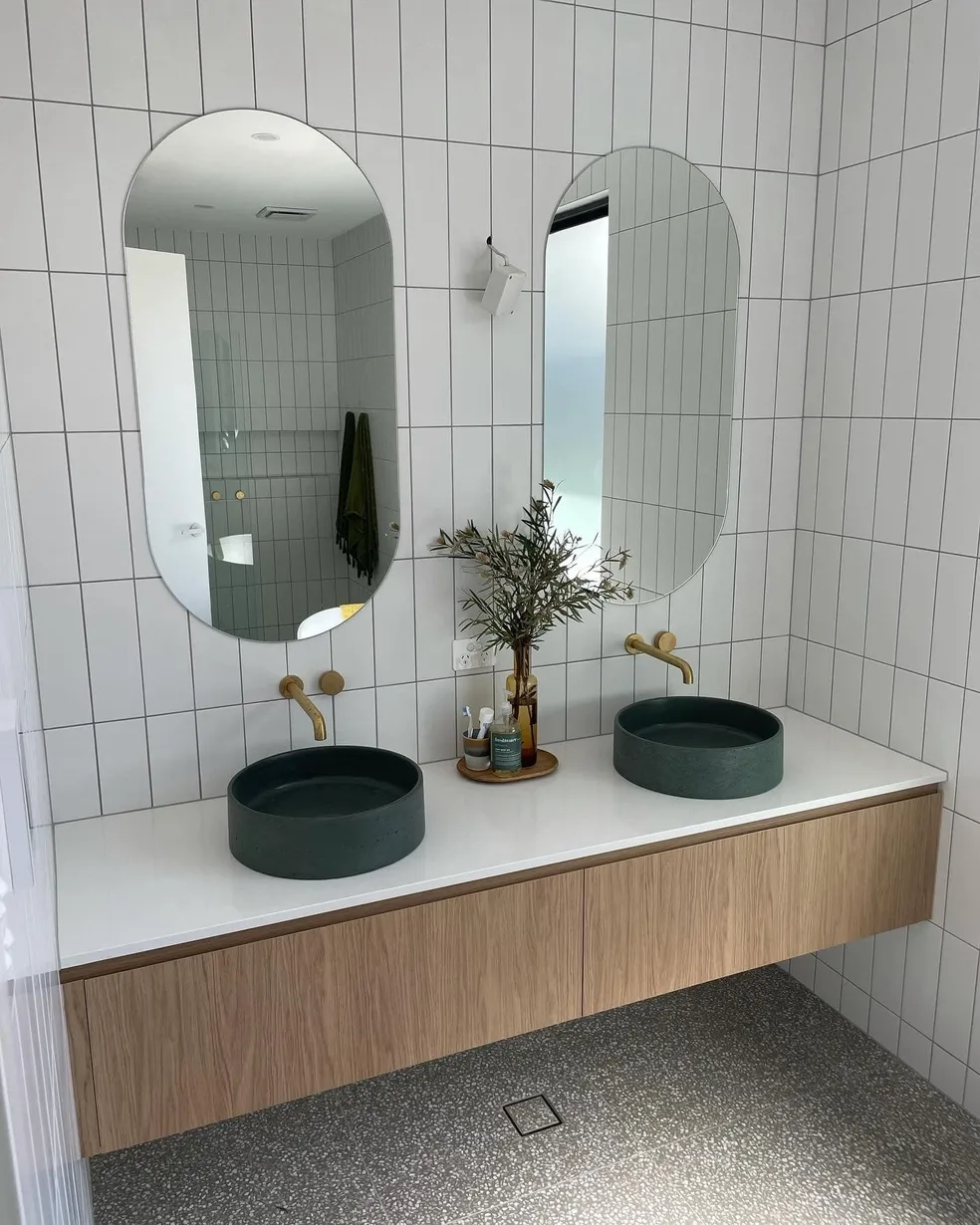 Dual oak floating vanity with dark vessel sinks, gold tapware and vertical white tiles