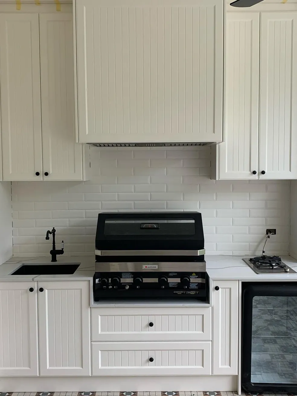 Coastal white beadboard kitchen with integrated BBQ and marble benchtop