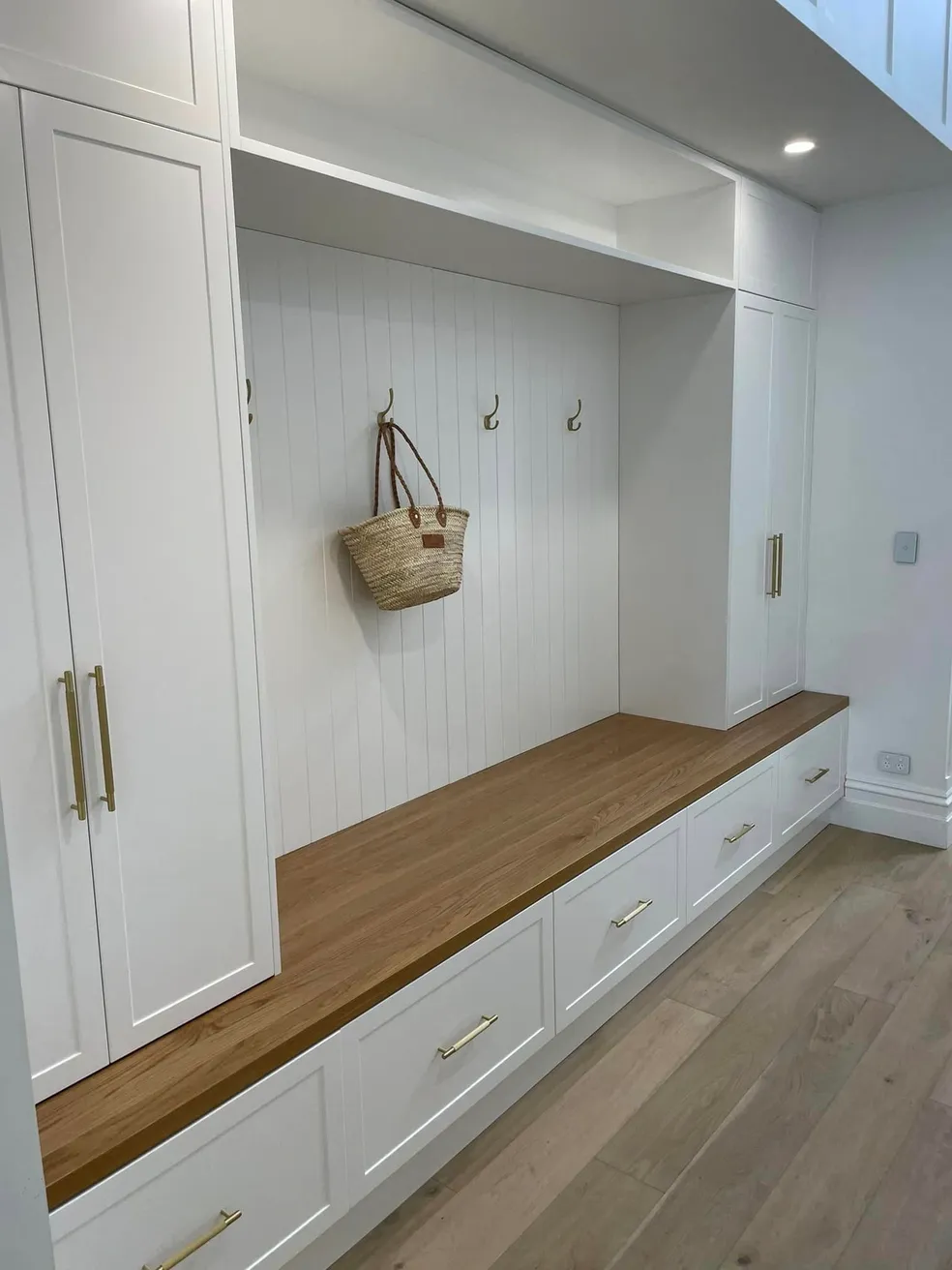 Hamptons white shaker mudroom with timber bench seat and brass coat hooks
