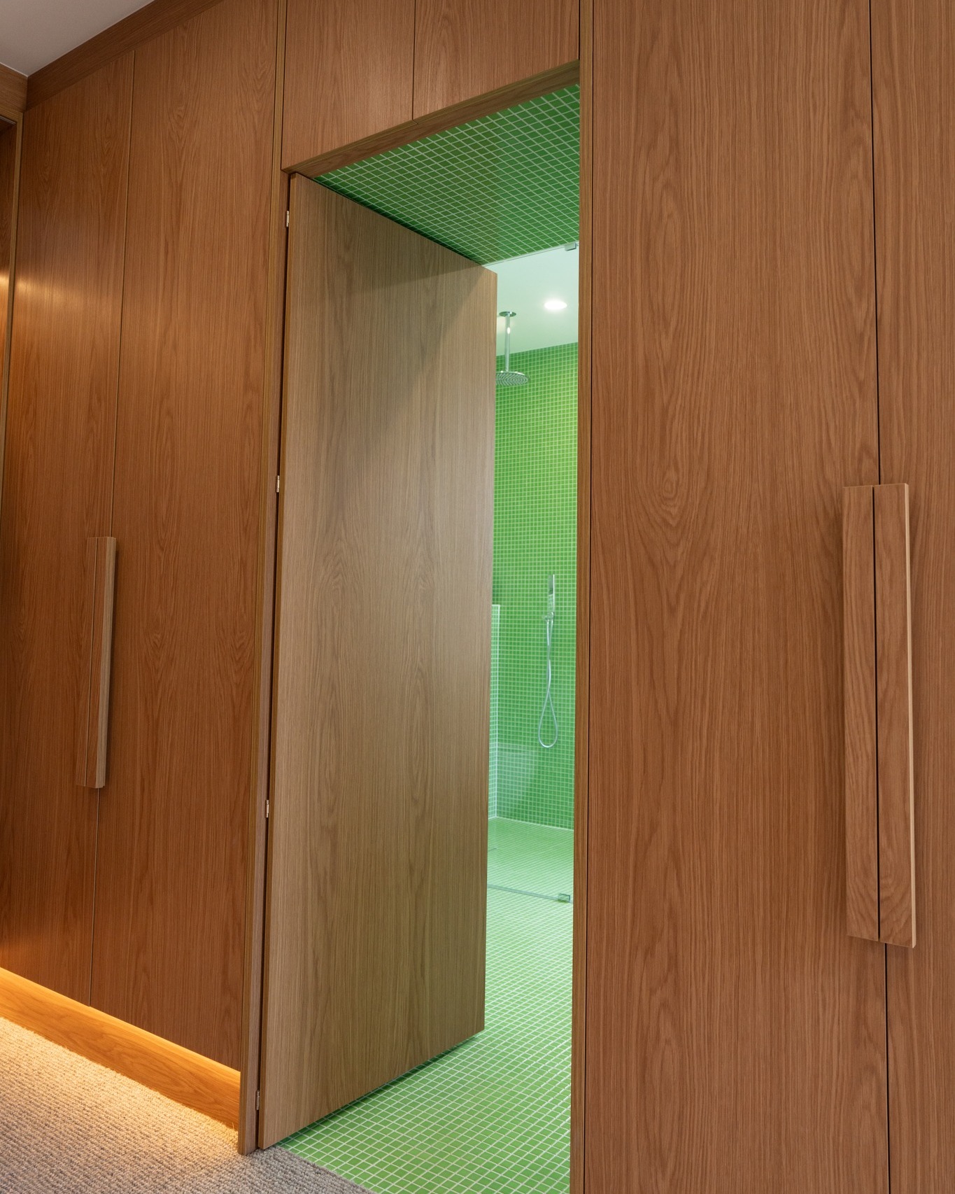 Floor-to-ceiling timber wardrobe panelling with hidden pivot door