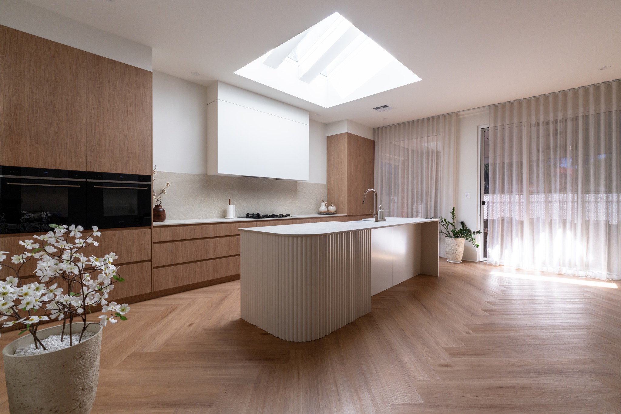 Hamptons kitchen with curved fluted island bench and skylight