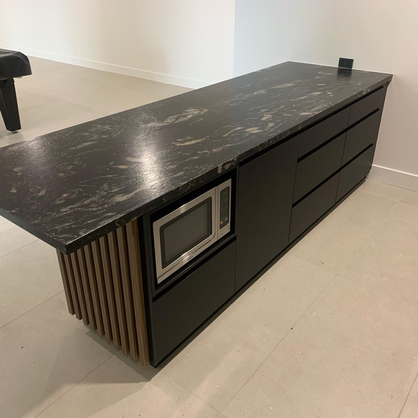 Custom commercial kitchen island with black marble benchtop and fluted timber base