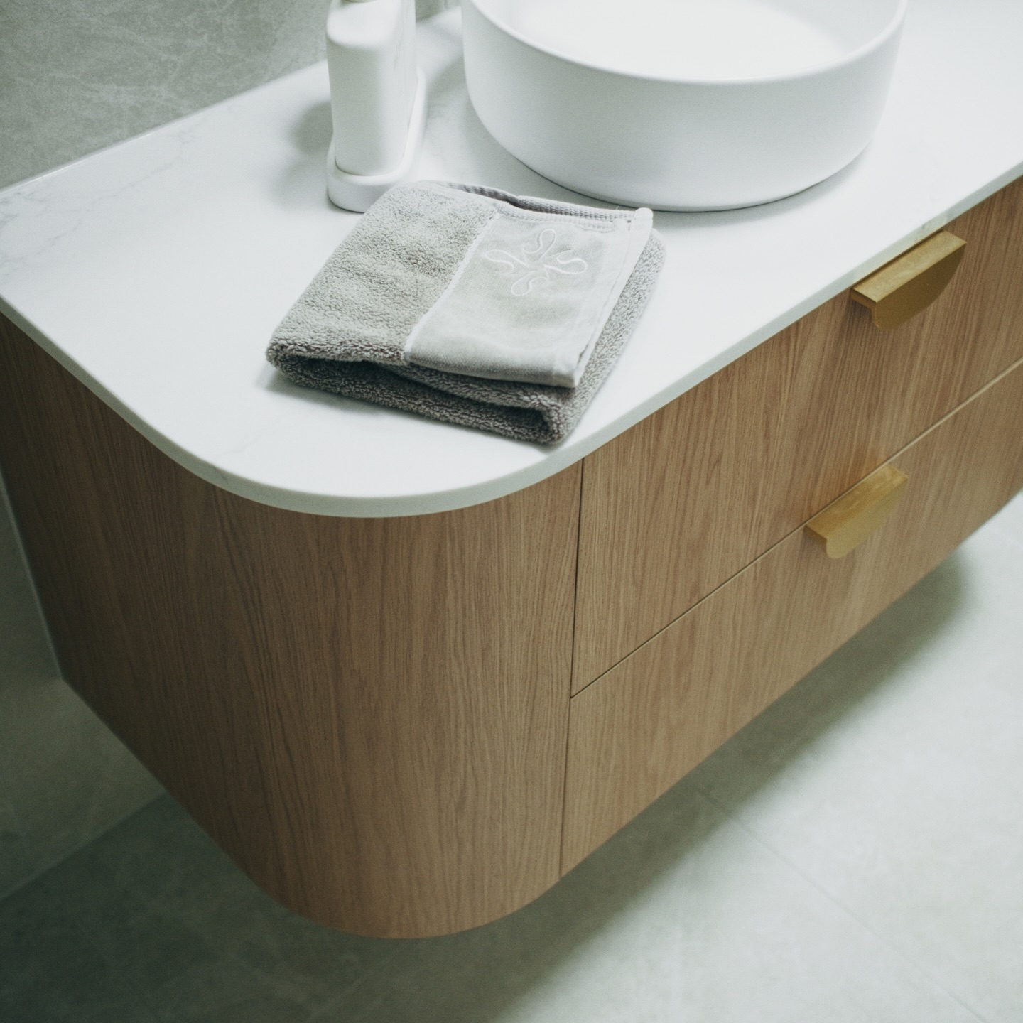 Curved floating oak vanity with vessel sink, stone benchtop and brushed gold handles